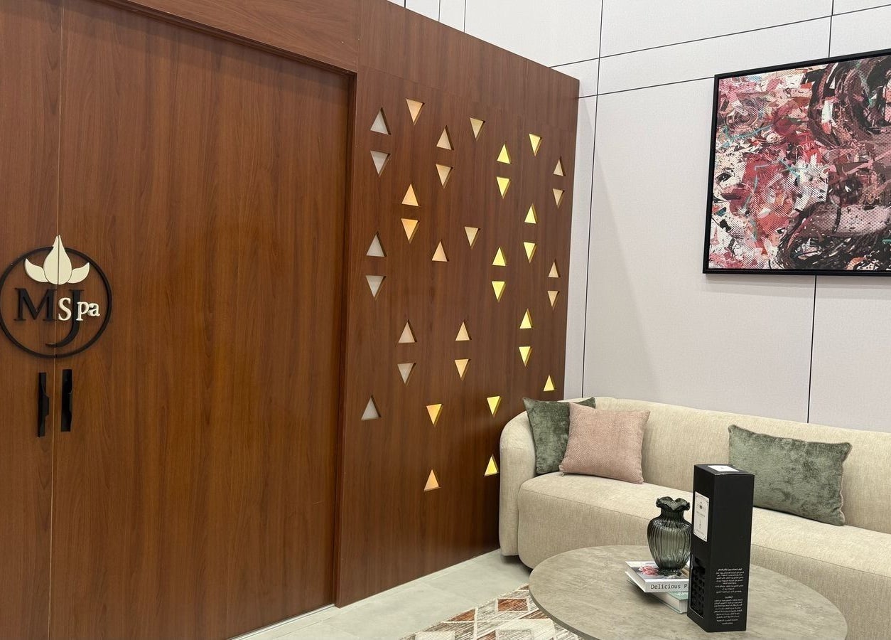 Elegant entrance at Mj Spa, Riyadh. Cozy sofa, artwork, and warm wooden accents invite relaxation.