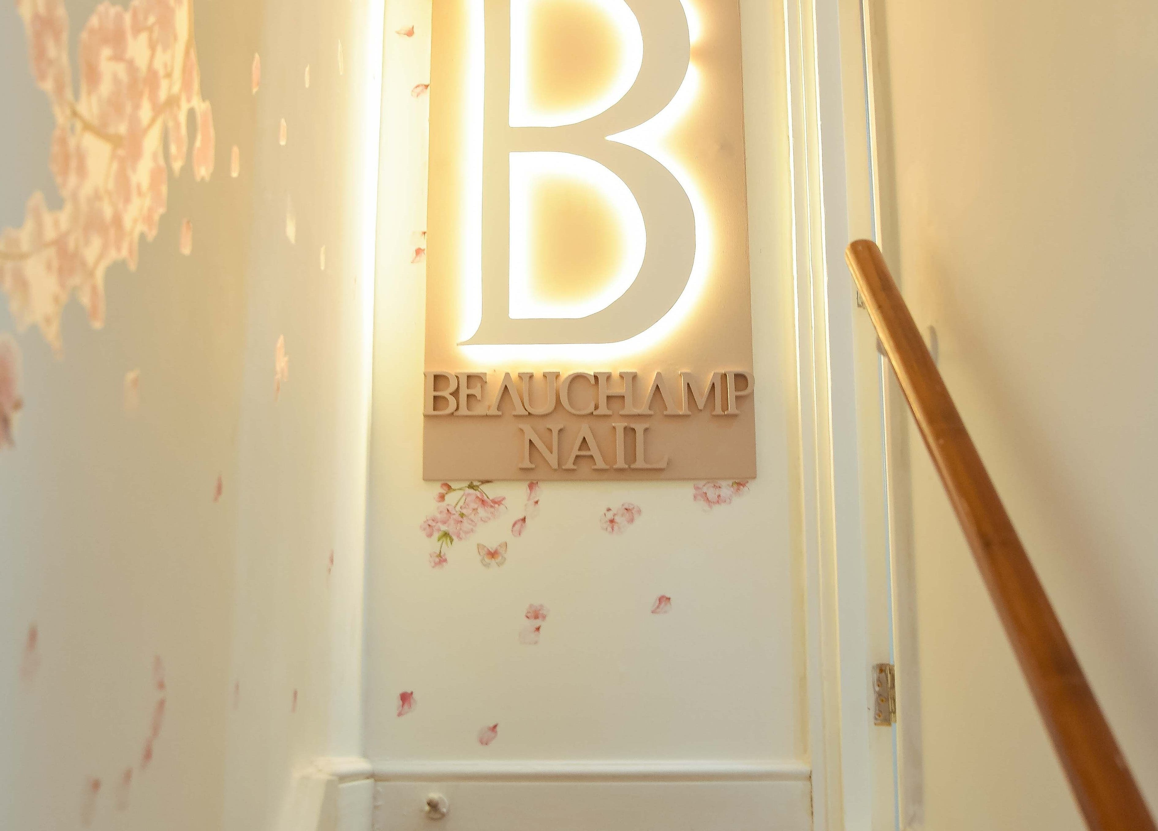 Beauchamp Nails Bar entrance sign warmly lit, located in London, England, GB. Inviting ambiance and charming decor.