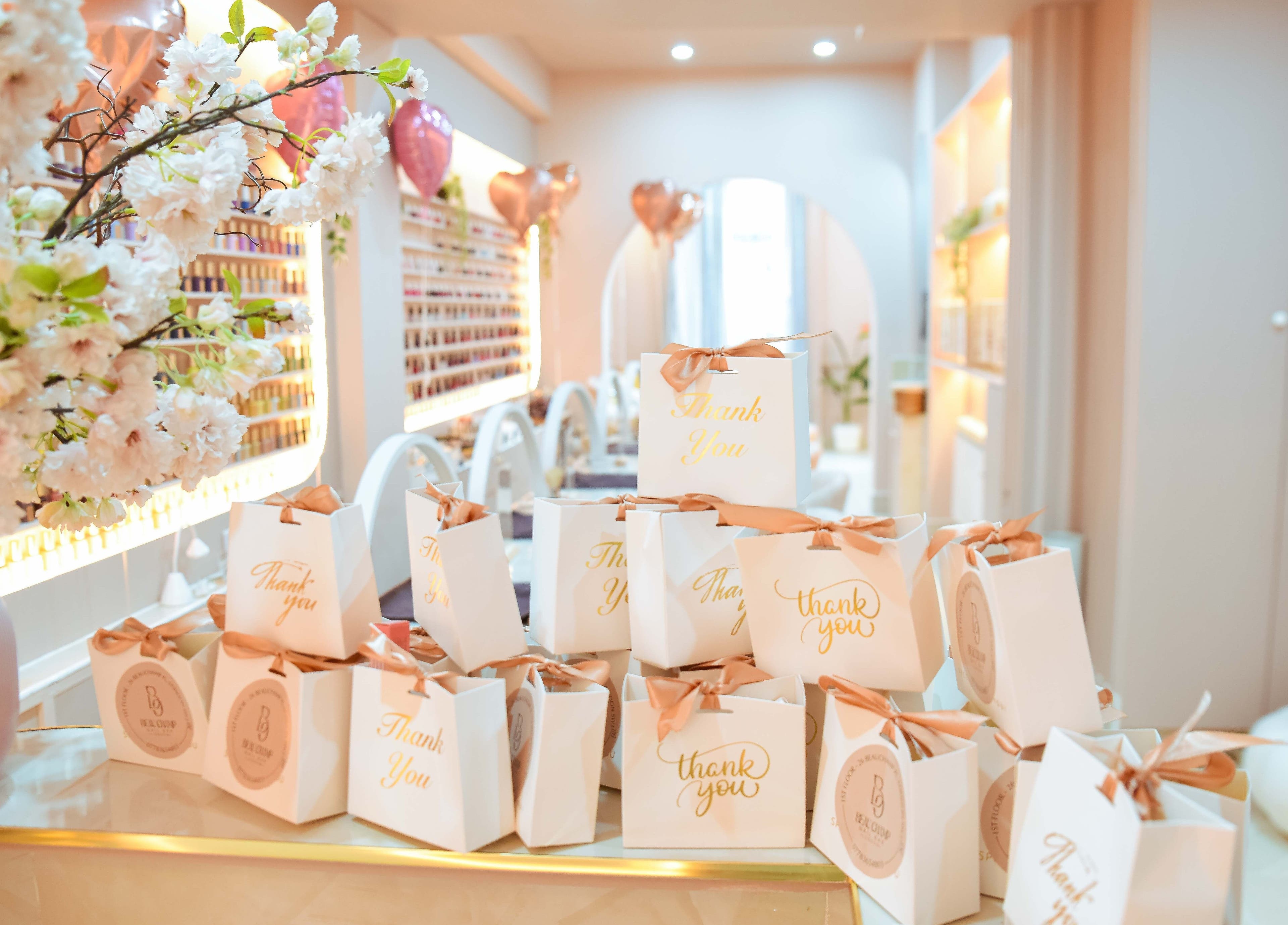 Elegant gift bags at Beauchamp Nails Bar, London, England, GB, surrounded by soft decor and floral arrangements.