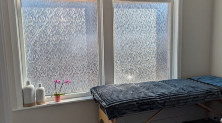 Relaxing massage table near frosted windows at The Backdoor Wax Studio in Trail, British Columbia, CA.