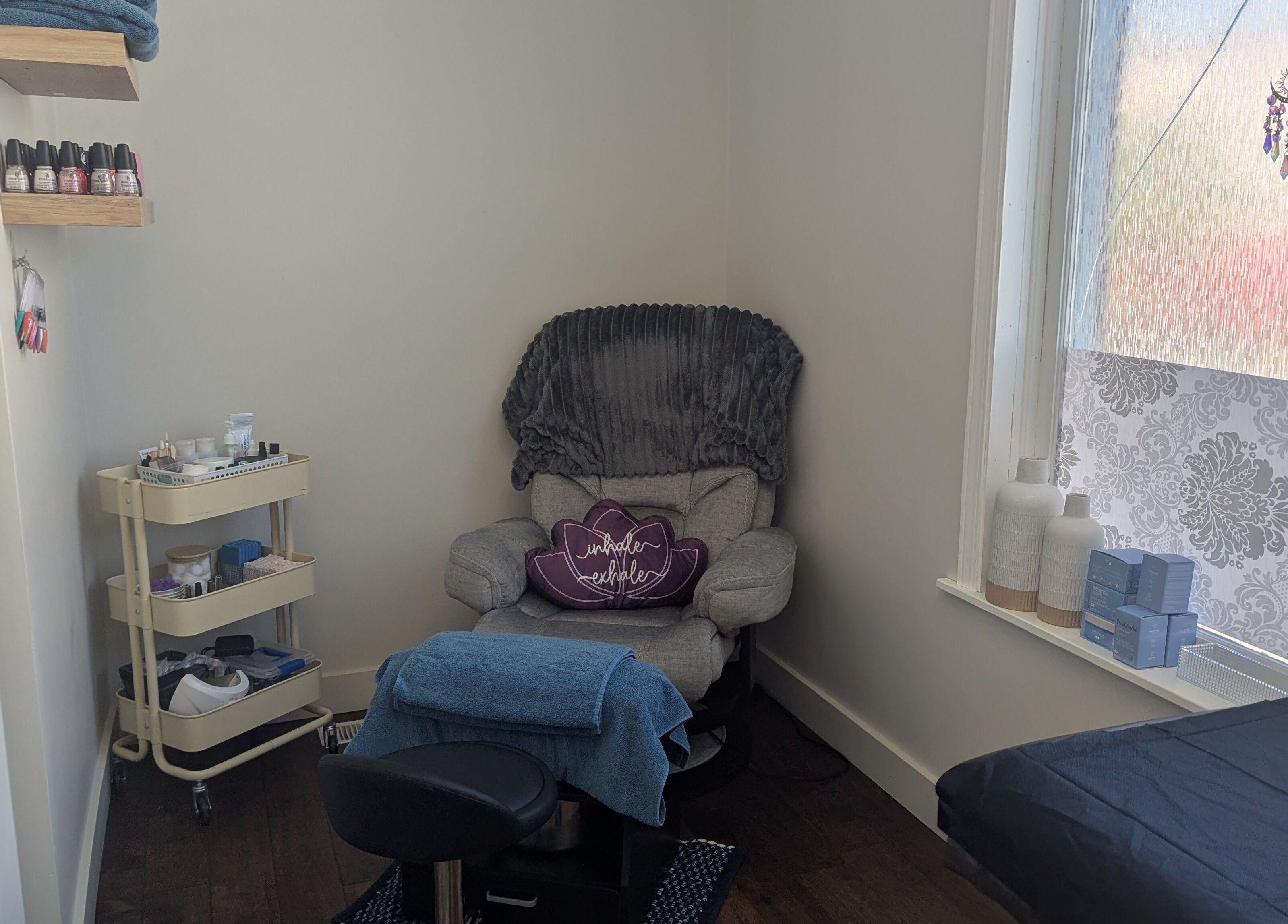 Relaxing corner at The Backdoor Wax Studio in Trail, British Columbia, CA, featuring a plush chair and essentials.