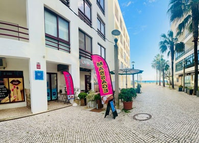Entrance to Talay Thai Massage Therapy in Quarteira, Faro, PT with vibrant display signs and beach view.