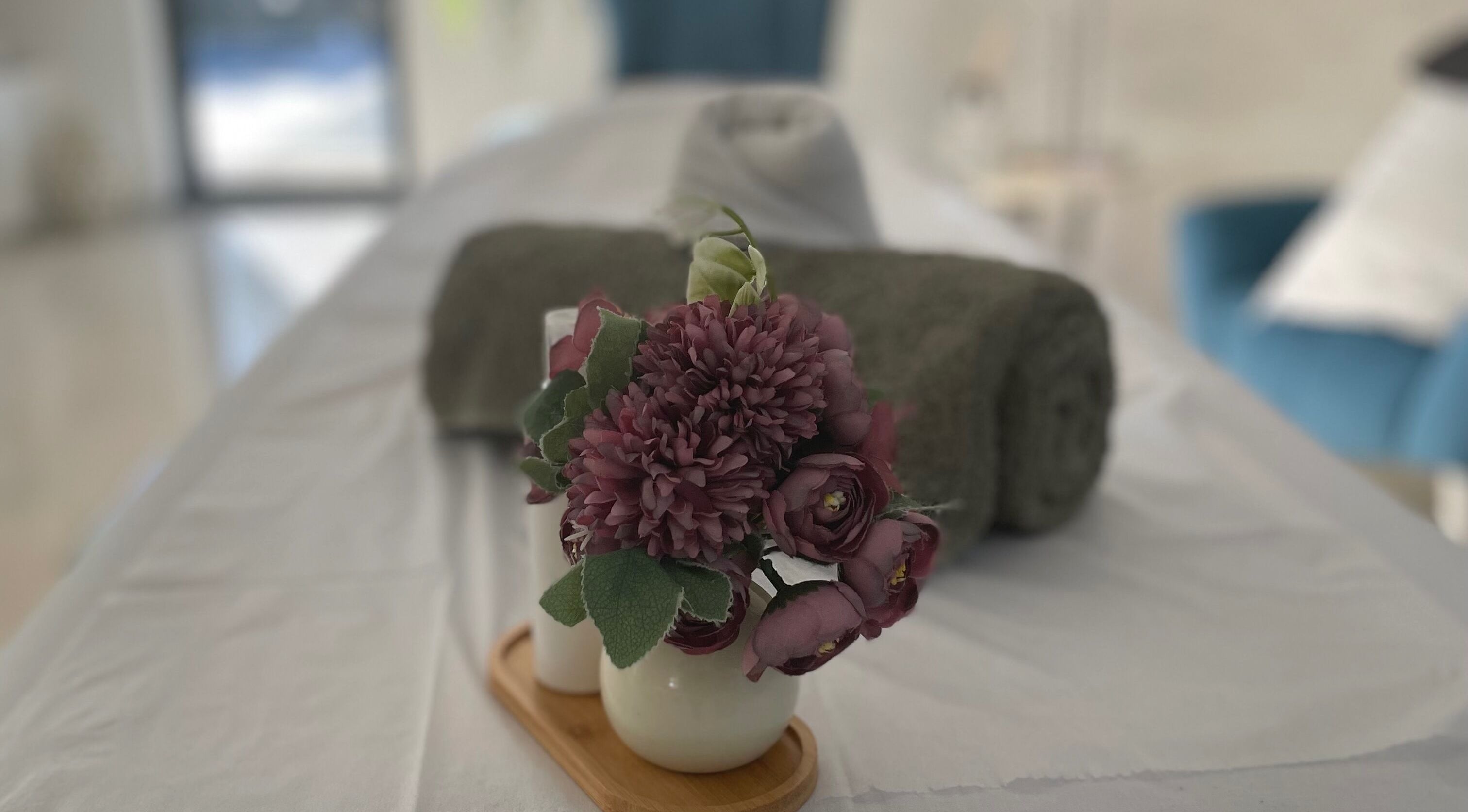 Elegant massage room at Home Massage&Therapies, Albufeira with fresh flowers and towels on the table.