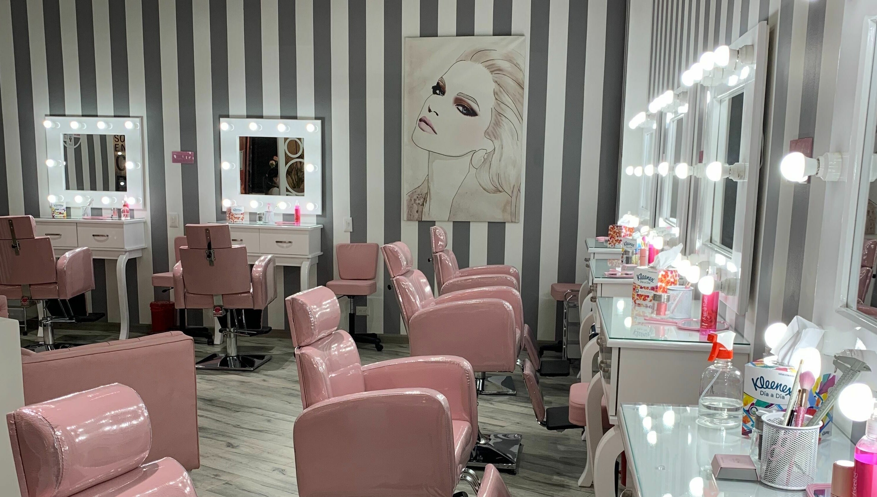 Interior elegante de salón en Le Visage Parque la Colina, Bogotá, CO con sillas rosadas y espejos iluminados.