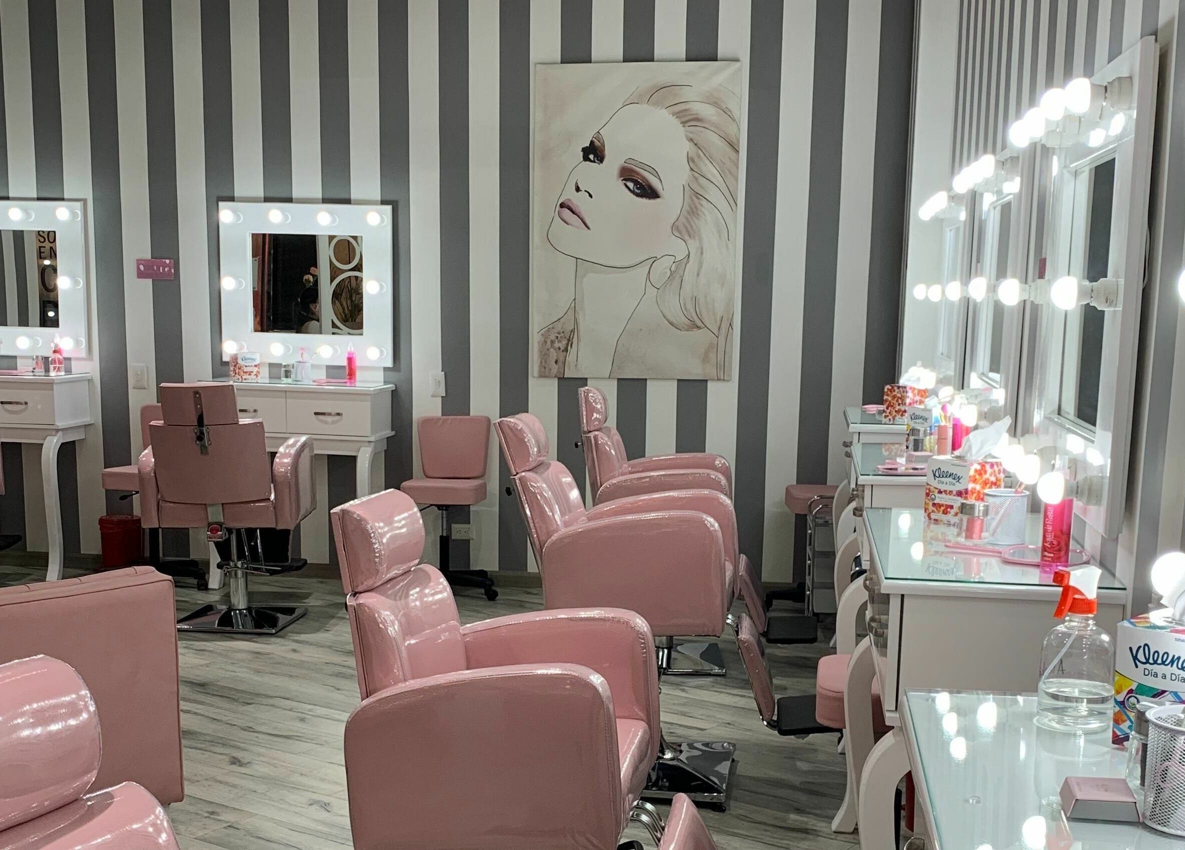 Interior elegante de salón en Le Visage Parque la Colina, Bogotá, CO con sillas rosadas y espejos iluminados.