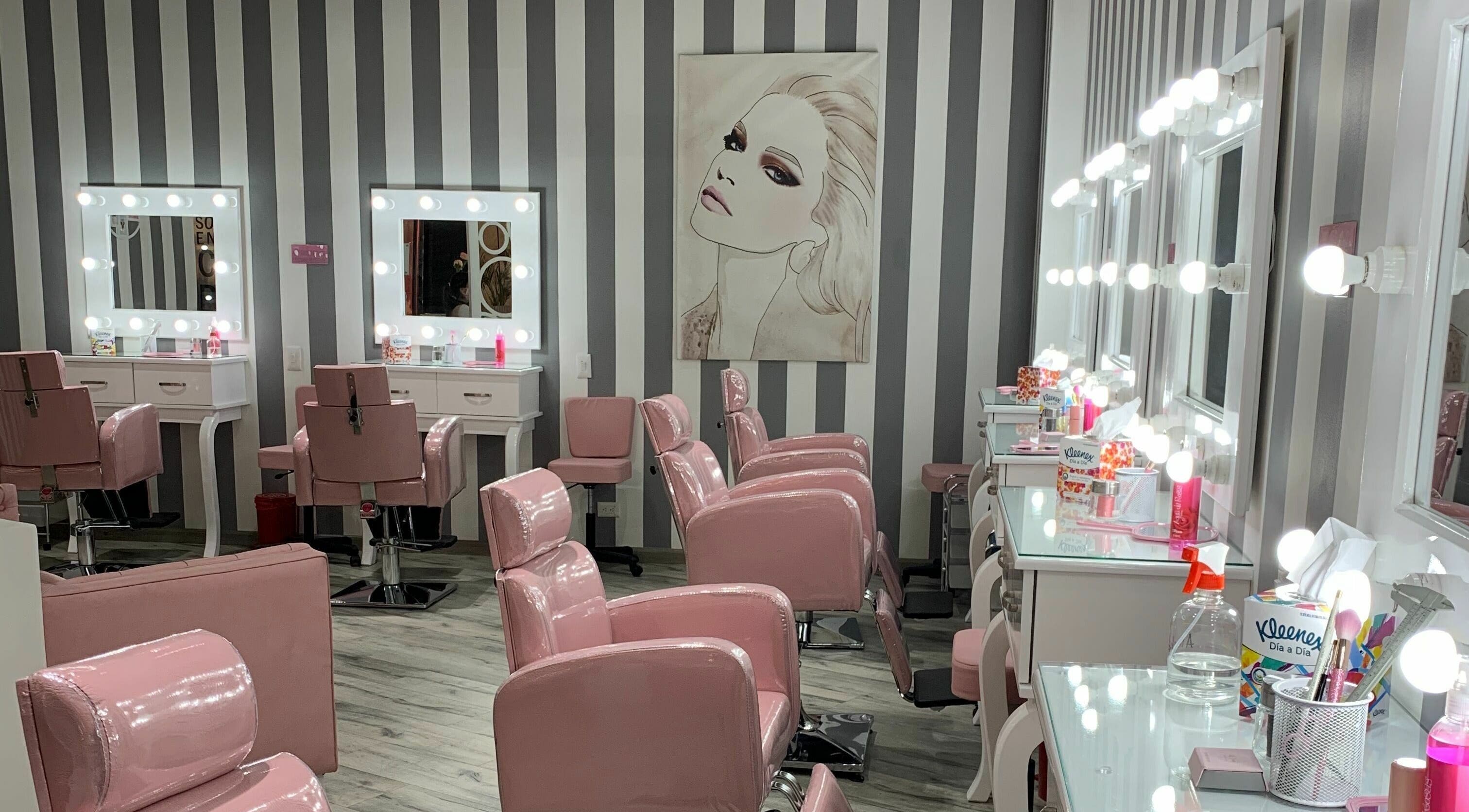 Interior elegante de salón en Le Visage Parque la Colina, Bogotá, CO con sillas rosadas y espejos iluminados.