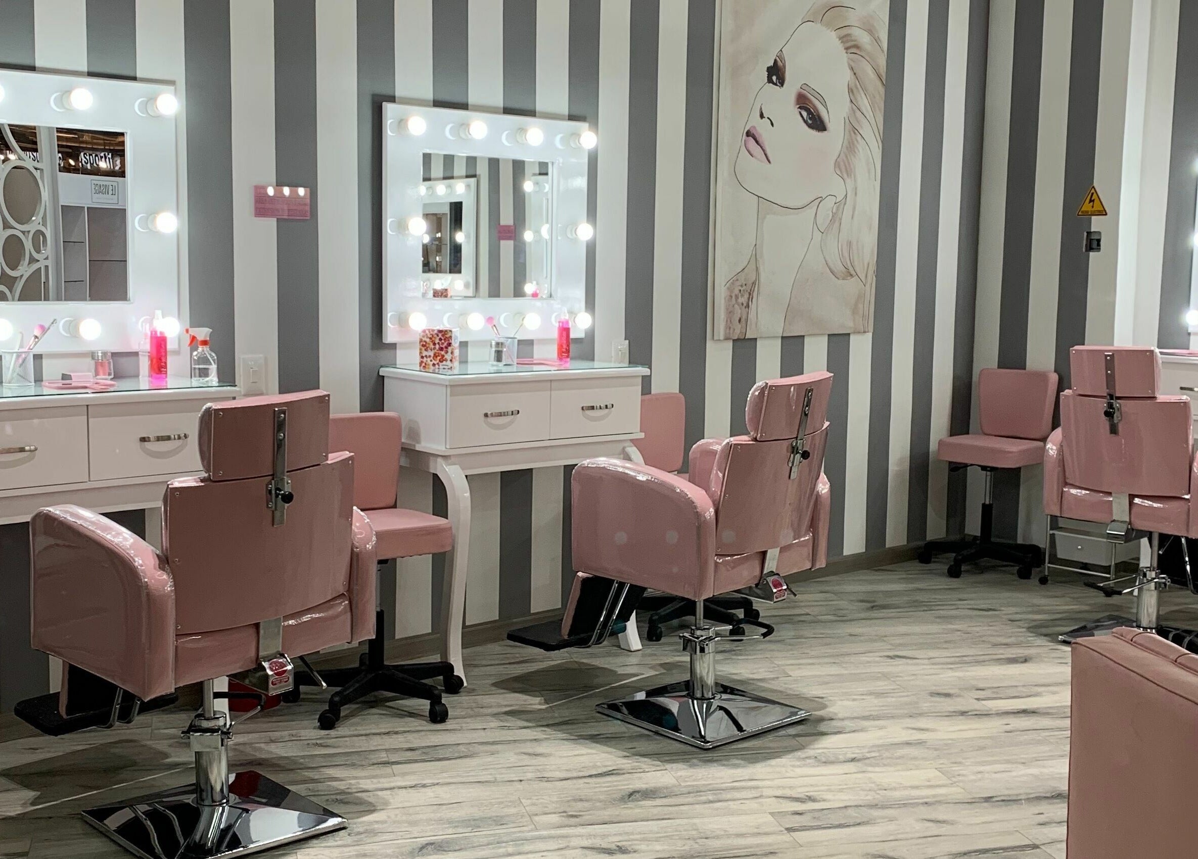 Estética moderna de Le Visage Parque la Colina, Bogotá, CO, con espejos iluminados y sillas rosas.