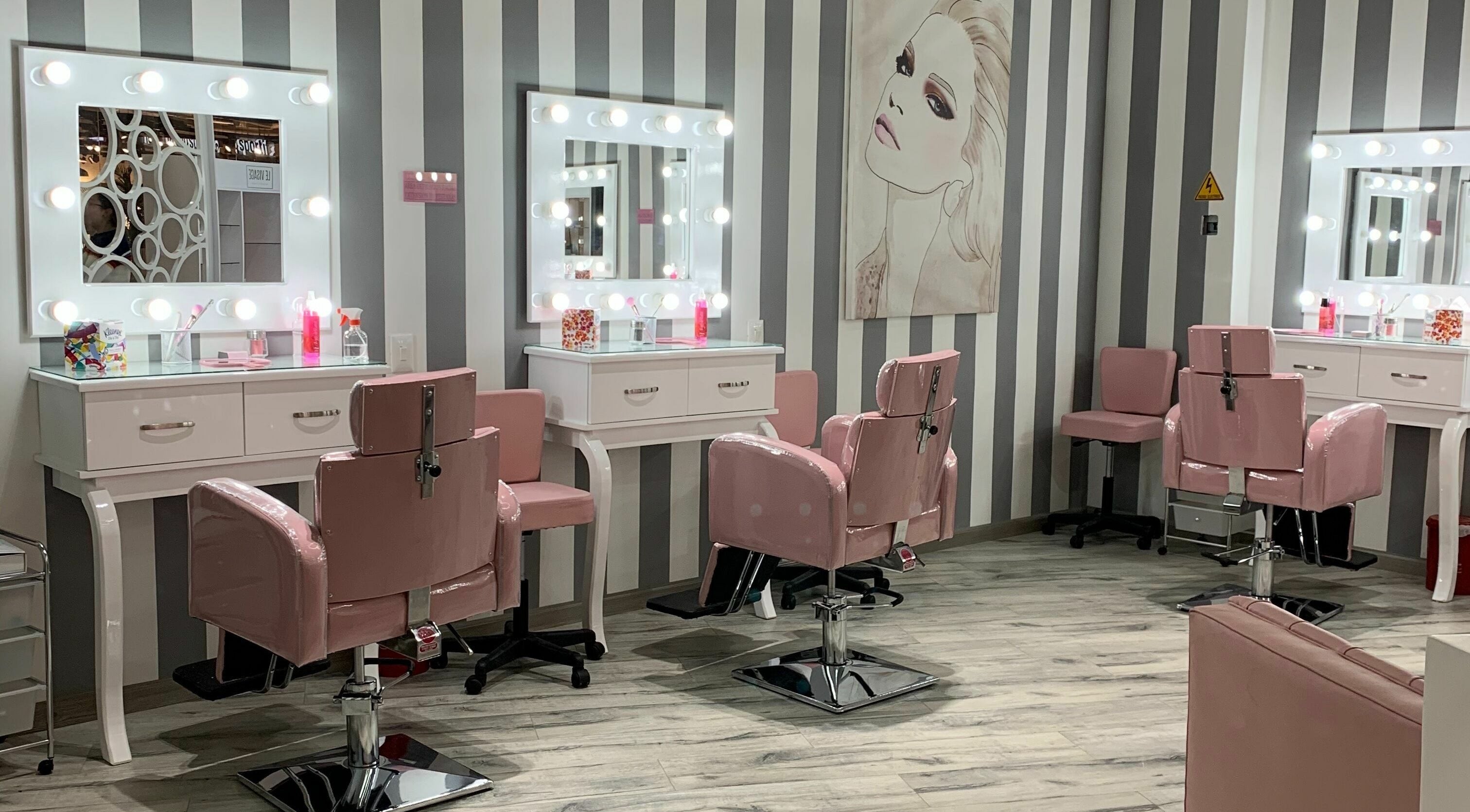 Estética moderna de Le Visage Parque la Colina, Bogotá, CO, con espejos iluminados y sillas rosas.