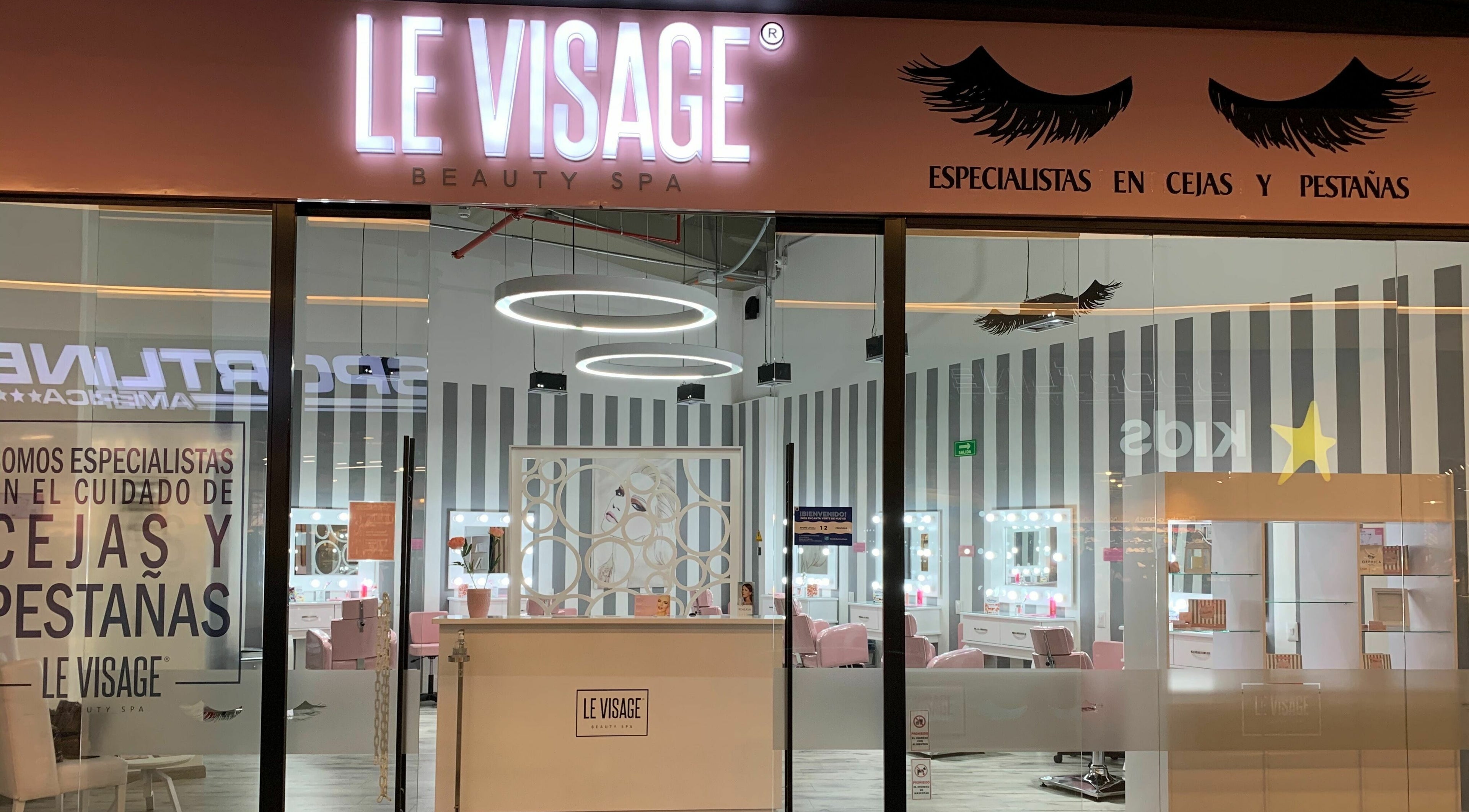 Fachada iluminada de Le Visage Parque la Colina en Bogotá, CO, especializada en cejas y pestañas.