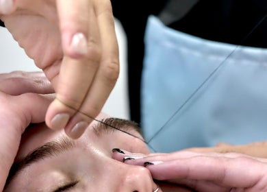 Eyebrow threading at Diamond Beauty, Surrey, British Columbia, CA. Close-up of hands shaping perfect brows.