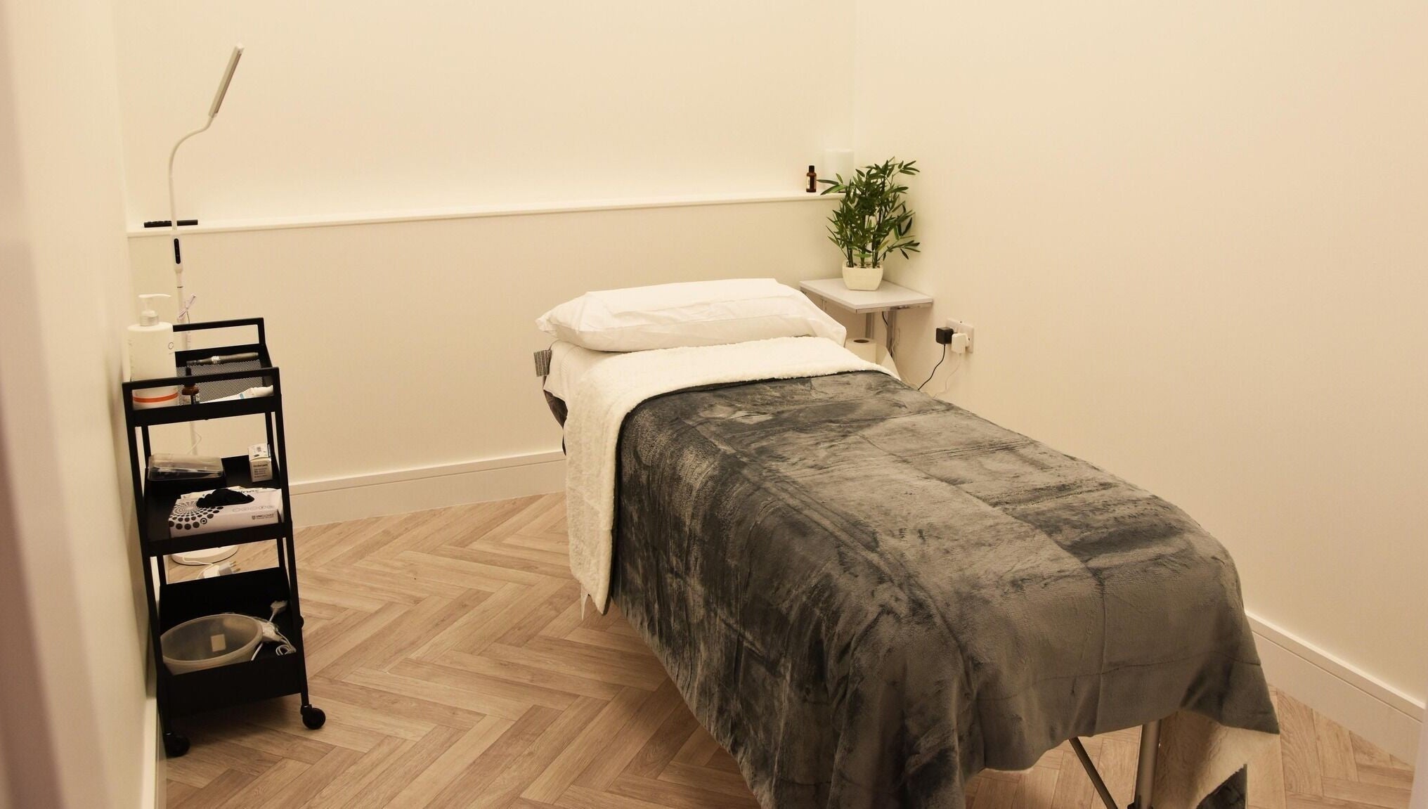 Cozy treatment room at Ace Aesthetics, Ramelton, County Donegal, IE, featuring a plush bed and sleek cart.