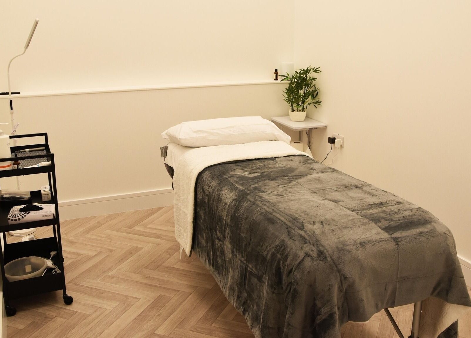 Cozy treatment room at Ace Aesthetics, Ramelton, County Donegal, IE, featuring a plush bed and sleek cart.