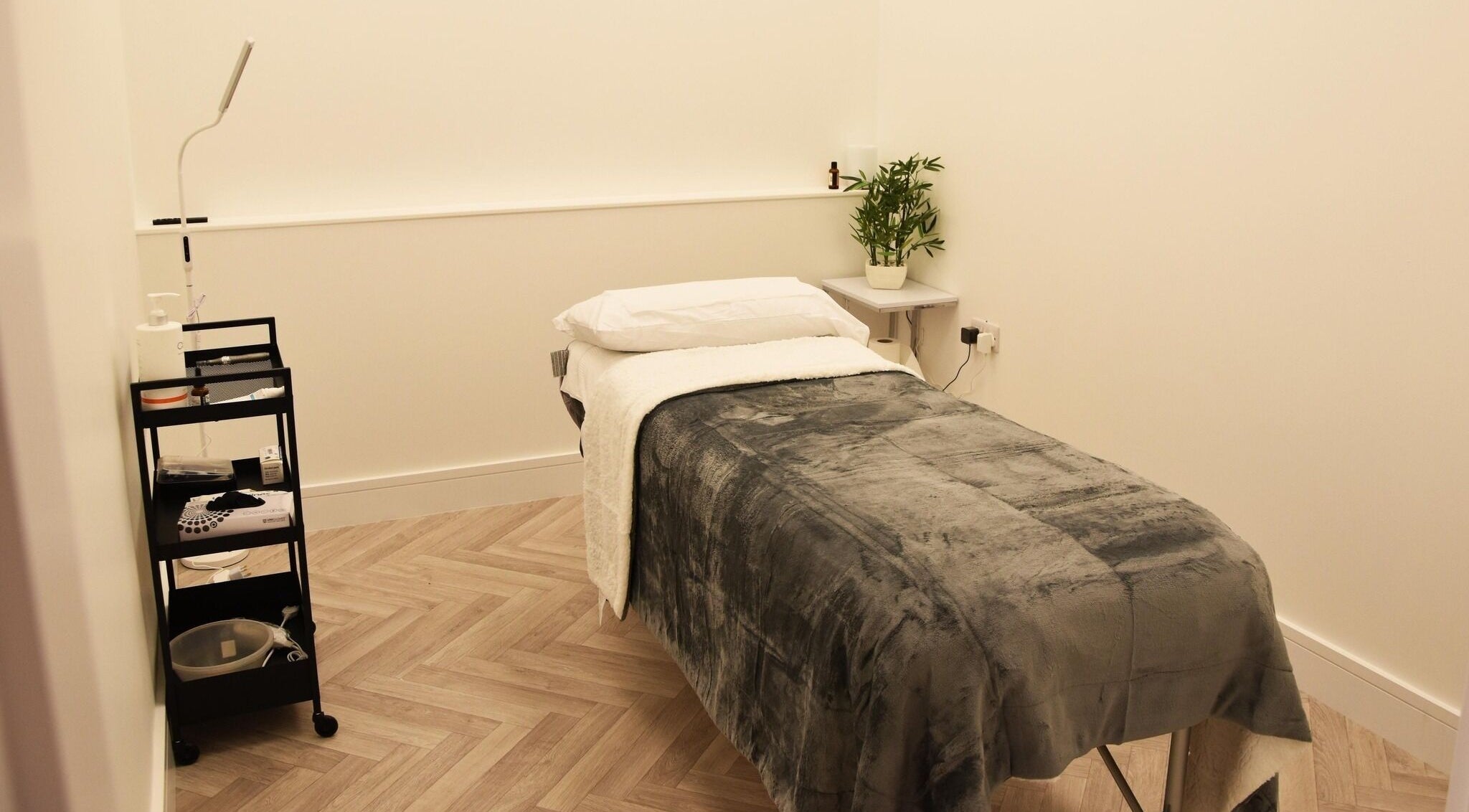Cozy treatment room at Ace Aesthetics, Ramelton, County Donegal, IE, featuring a plush bed and sleek cart.