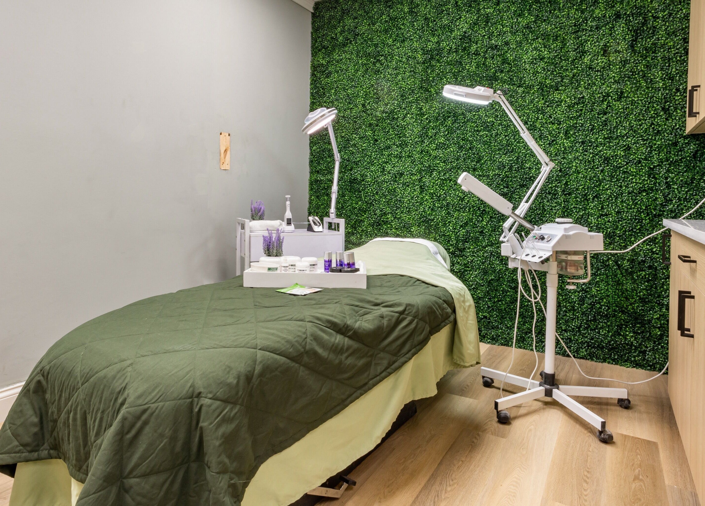 Relaxing treatment room at BEAUTYOLOGY, Ooltewah, Tennessee, US, featuring a green wall and spa essentials.