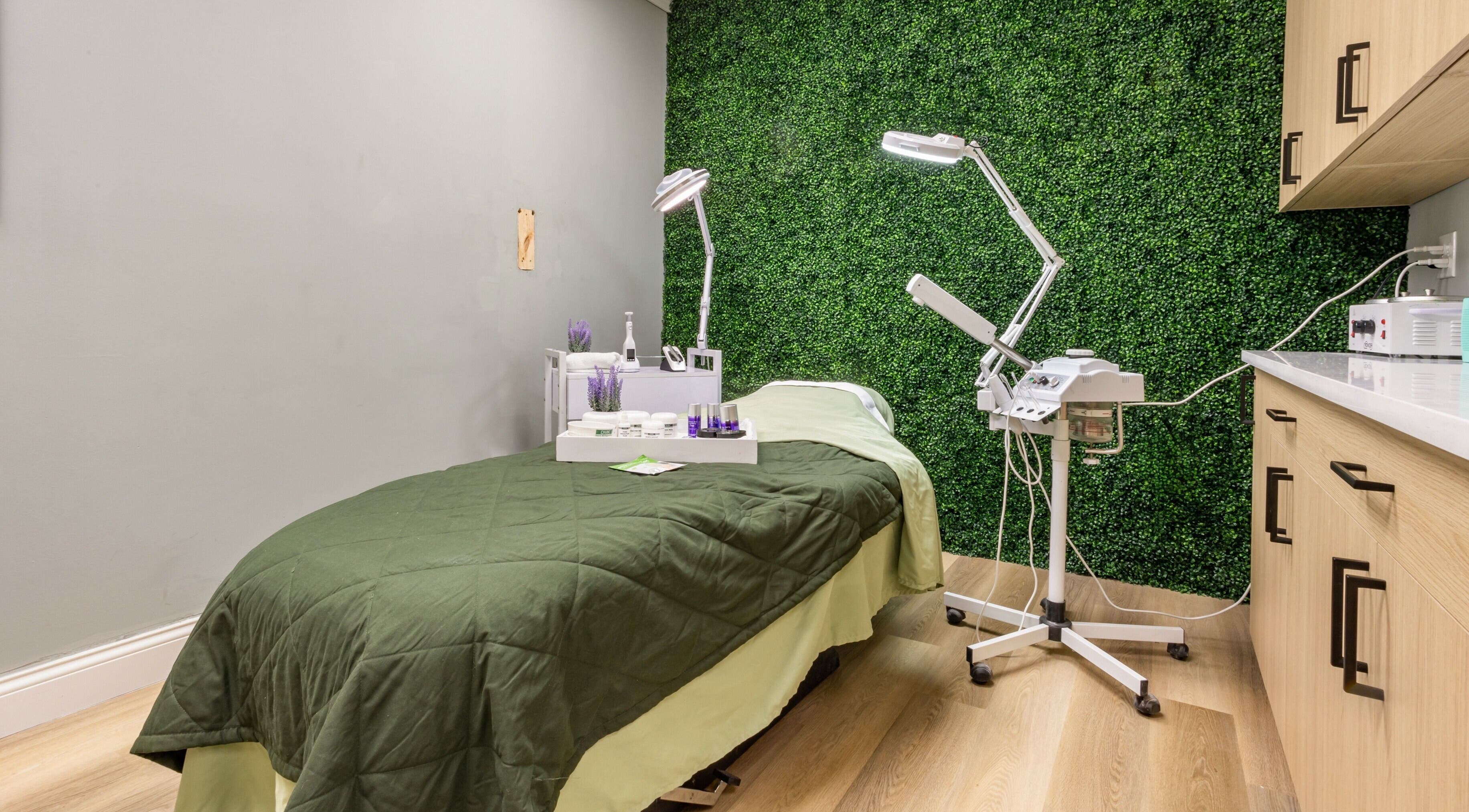 Relaxing treatment room at BEAUTYOLOGY, Ooltewah, Tennessee, US, featuring a green wall and spa essentials.