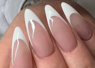 Close-up of elegant stiletto nails at Charlotte Amelia Beauty in Penryn, England, GB showcasing sleek white tips.