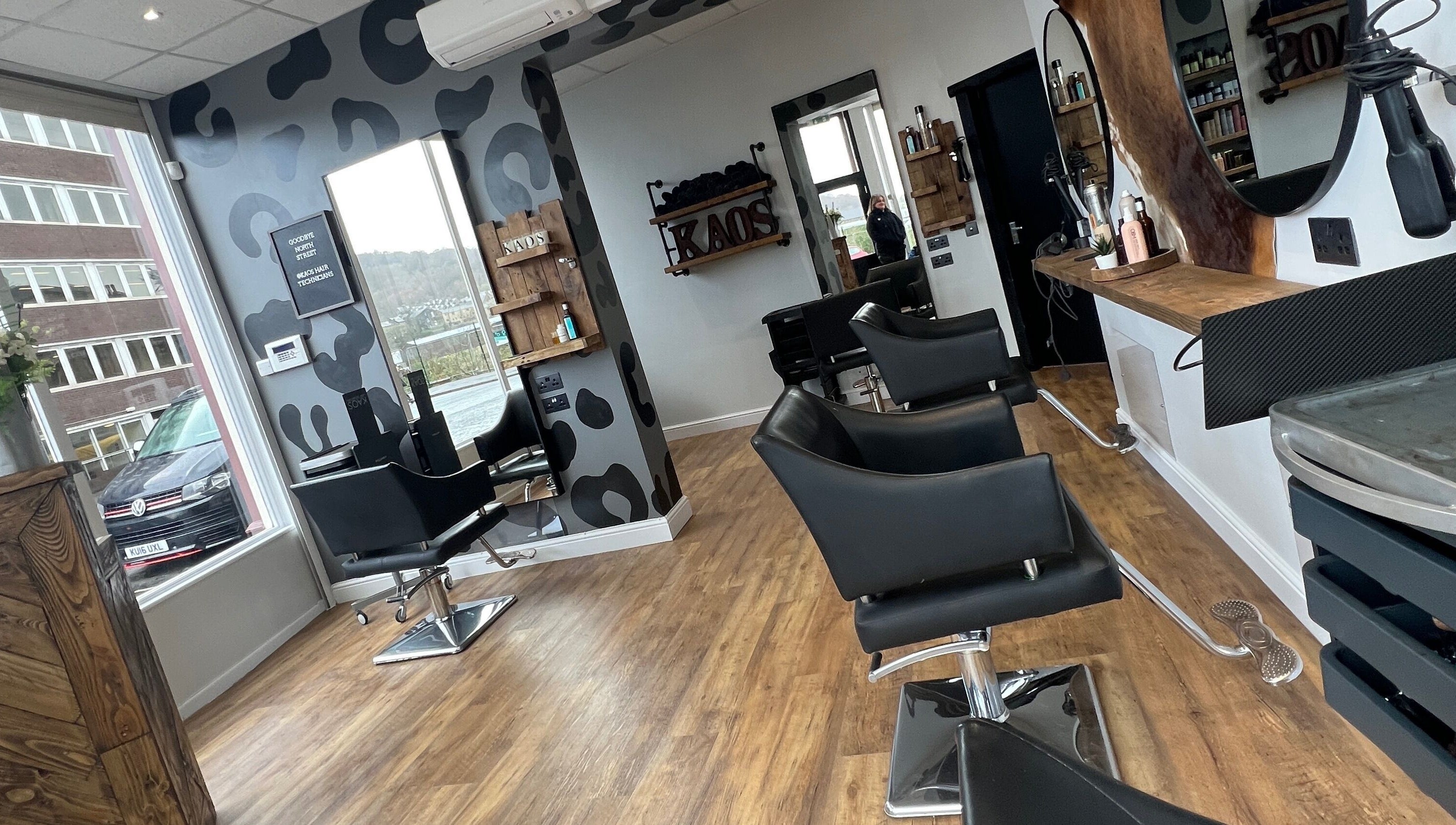 Modern interior of Kaos salon in Keighley, England, GB with stylish black chairs and wood accents.