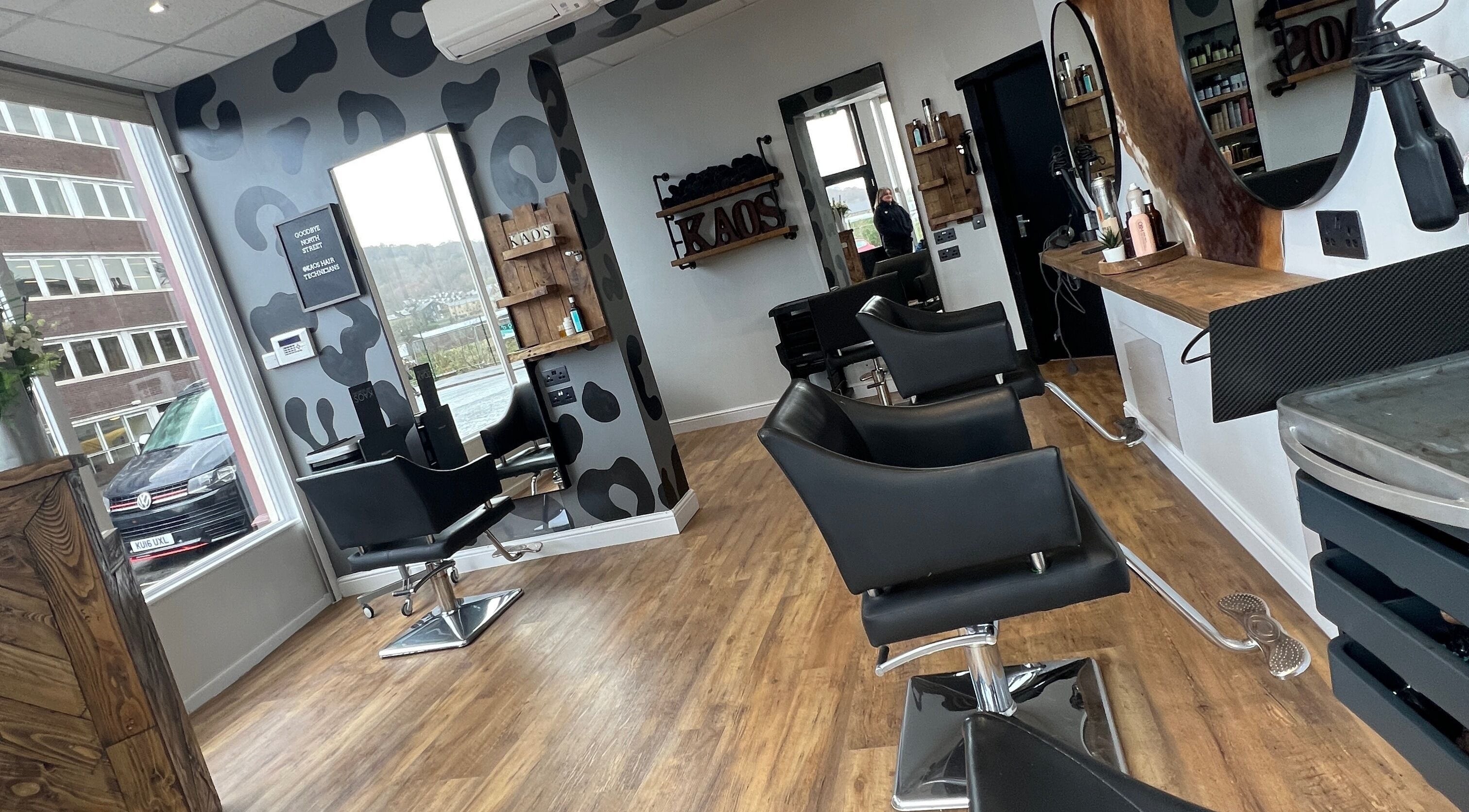 Modern interior of Kaos salon in Keighley, England, GB with stylish black chairs and wood accents.