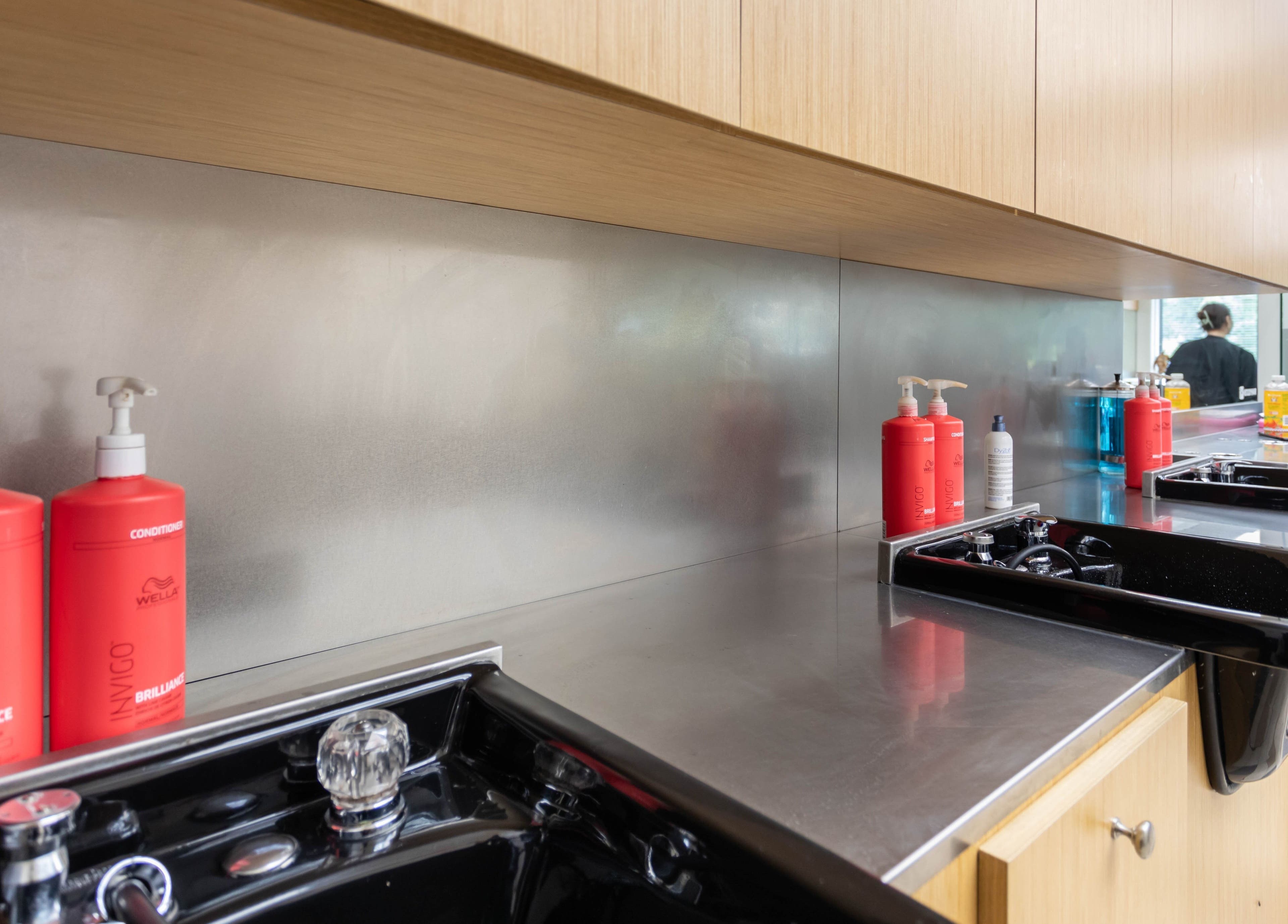 Modern salon wash station at IIC Wethersfield in Wethersfield, Connecticut, US with red shampoo bottles.