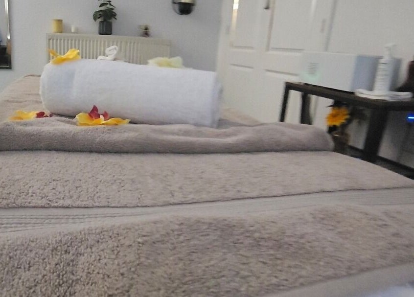 Cozy massage table at Heal and Restore by Mia in Llandudno, Wales, GB, adorned with towels and petals.