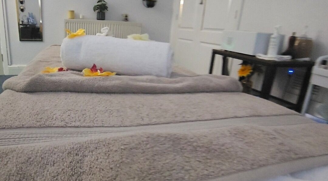 Cozy massage table at Heal and Restore by Mia in Llandudno, Wales, GB, adorned with towels and petals.