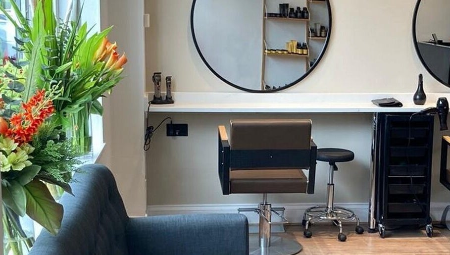 Interior of Rob Hicks Salon in Cheltenham, England featuring elegant styling station and fresh flowers.