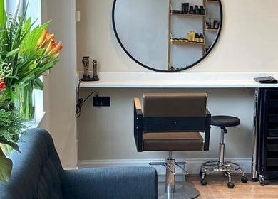 Interior of Rob Hicks Salon in Cheltenham, England featuring elegant styling station and fresh flowers.