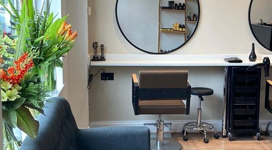 Interior of Rob Hicks Salon in Cheltenham, England featuring elegant styling station and fresh flowers.