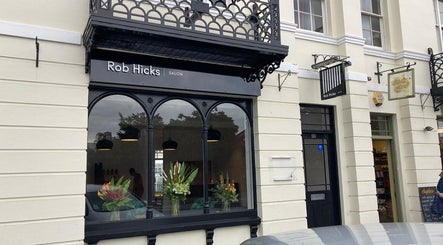 Exterior of Rob Hicks Salon in Cheltenham, England, GB featuring stylish black accents and floral displays.