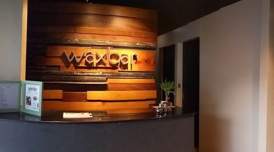 Reception area of Waxbar Teachers Village, Quezon City, PH, with a wooden wall and sleek counter.