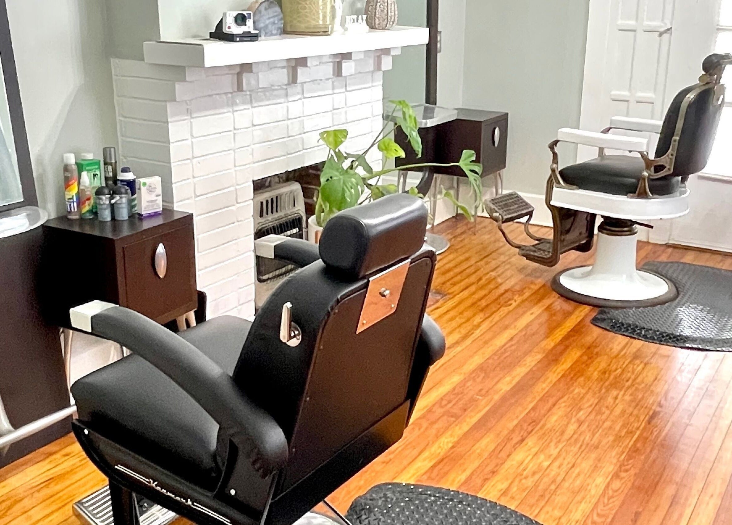 Chic interior of The Xperience Cut in New Orleans, Louisiana, US featuring stylish black salon chairs and wooden floor.