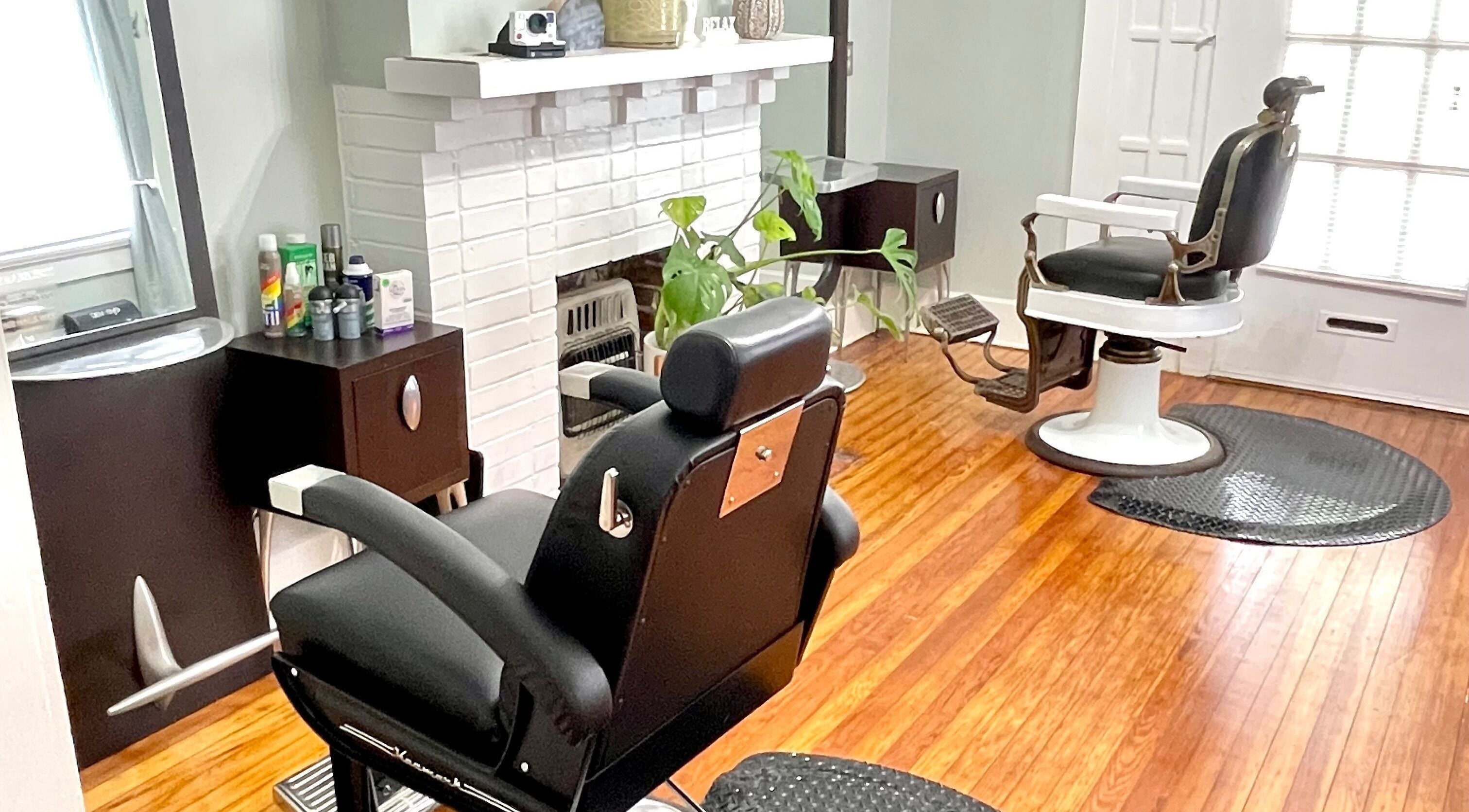 Chic interior of The Xperience Cut in New Orleans, Louisiana, US featuring stylish black salon chairs and wooden floor.