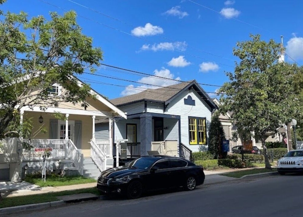 Charming house facade of The Xperience Cut in New Orleans, Louisiana, US with trees lining the street.
