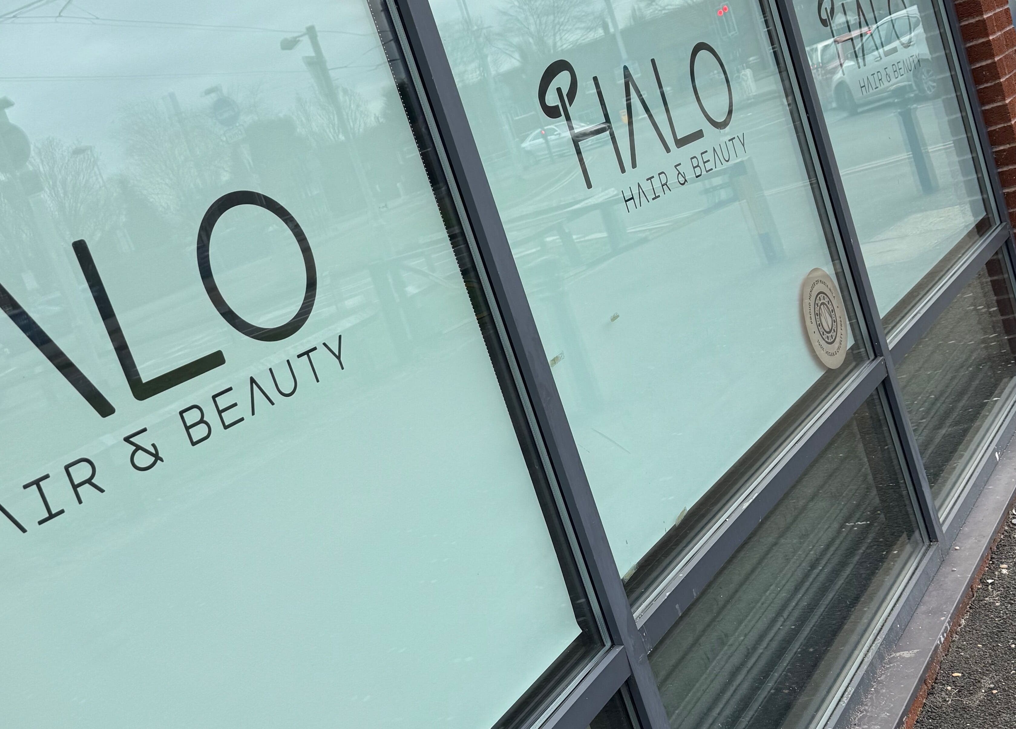 Glass facade of Halo Hair & Beauty in Wythenshawe, England, GB, showcasing elegant shop signage.