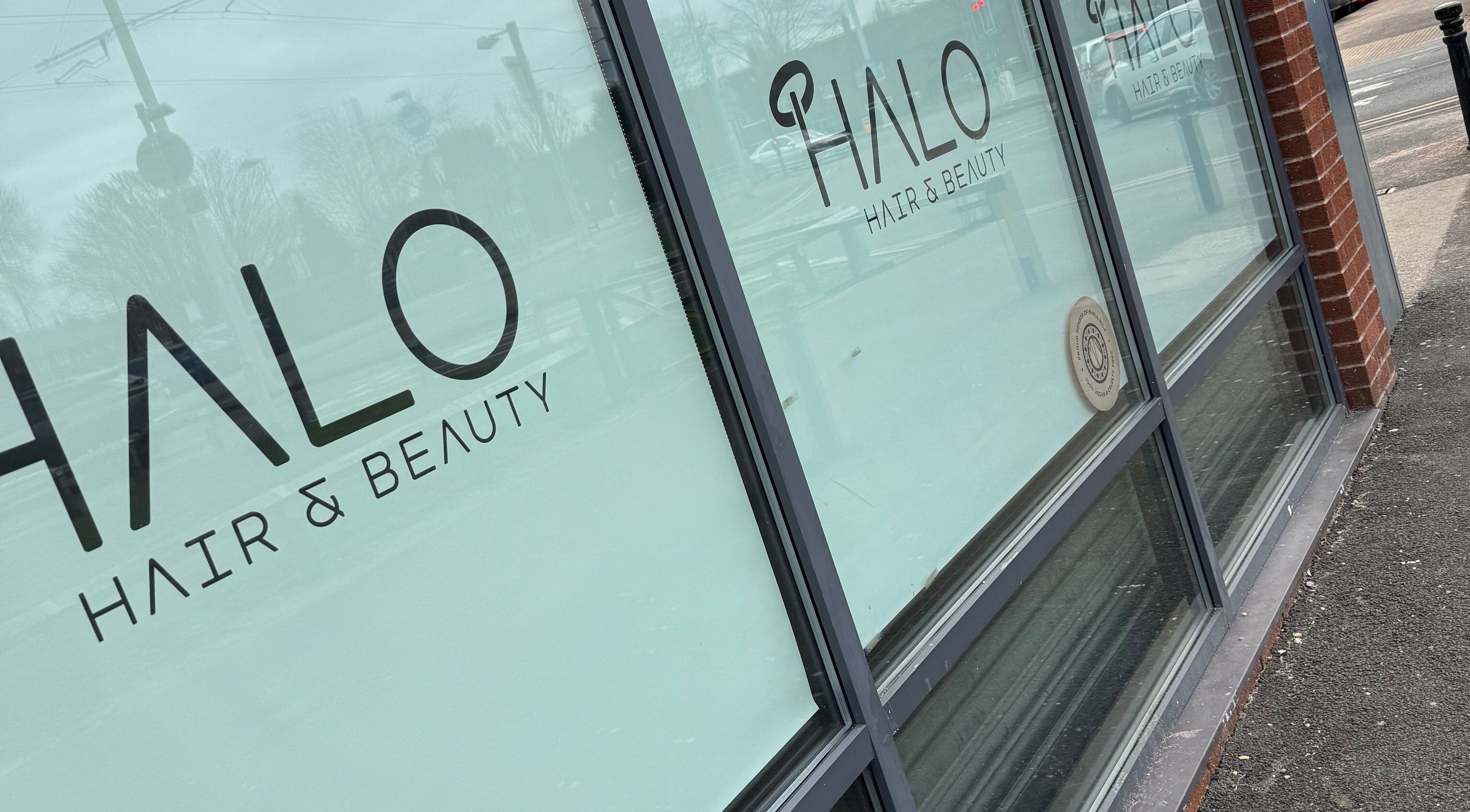Glass facade of Halo Hair & Beauty in Wythenshawe, England, GB, showcasing elegant shop signage.