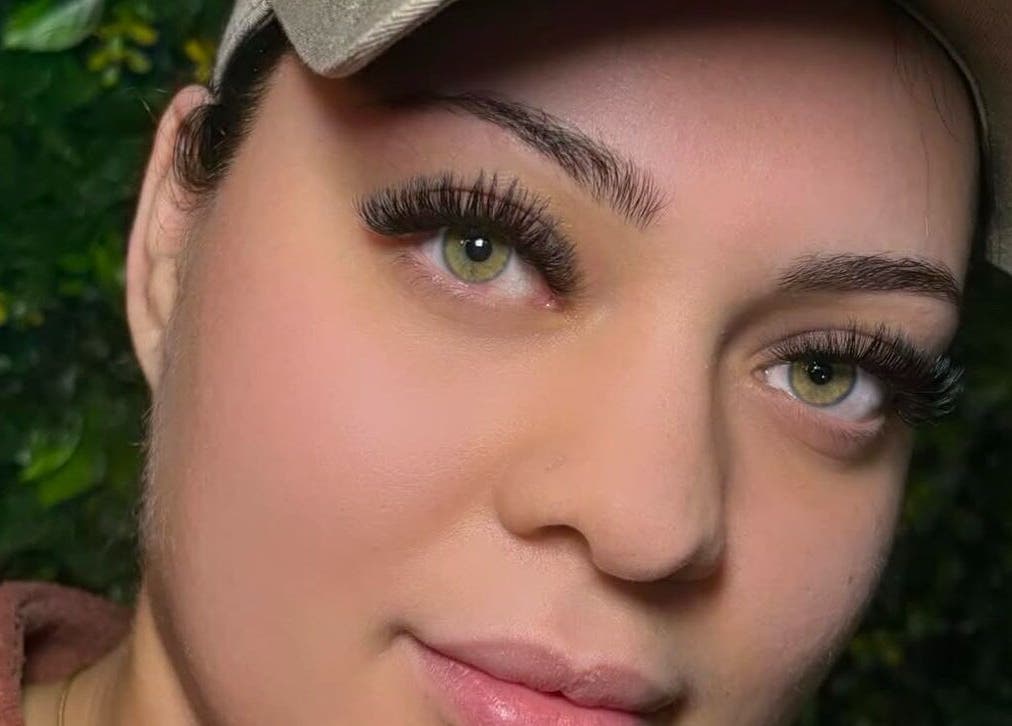 Close-up of elegant eyelash extensions at She Studios, London, Ontario, CA with a lush green background.