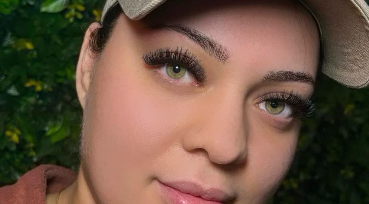 Close-up of elegant eyelash extensions at She Studios, London, Ontario, CA with a lush green background.