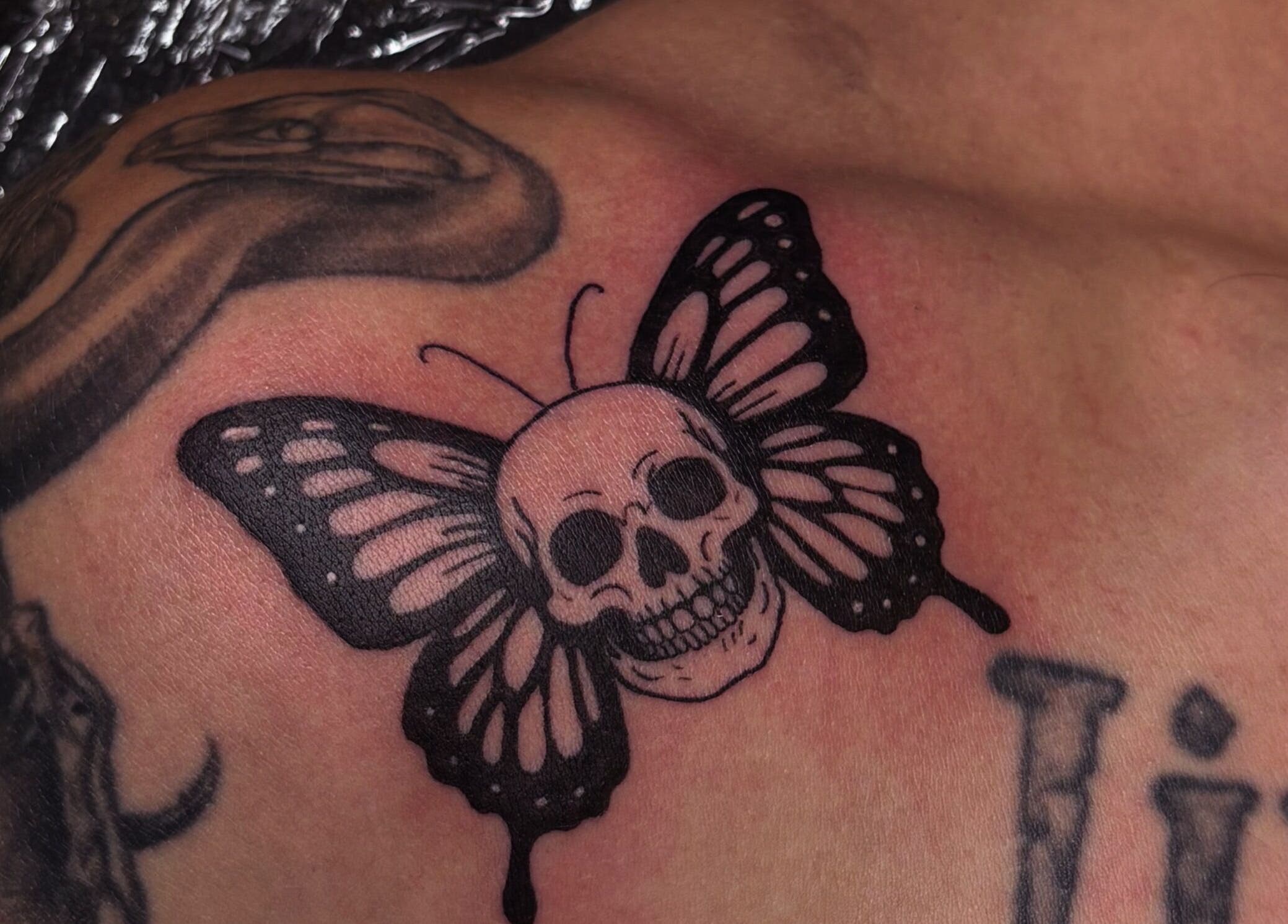 Bold skull butterfly tattoo art at She Studios, London, Ontario, CA, showcasing unique design and detail.