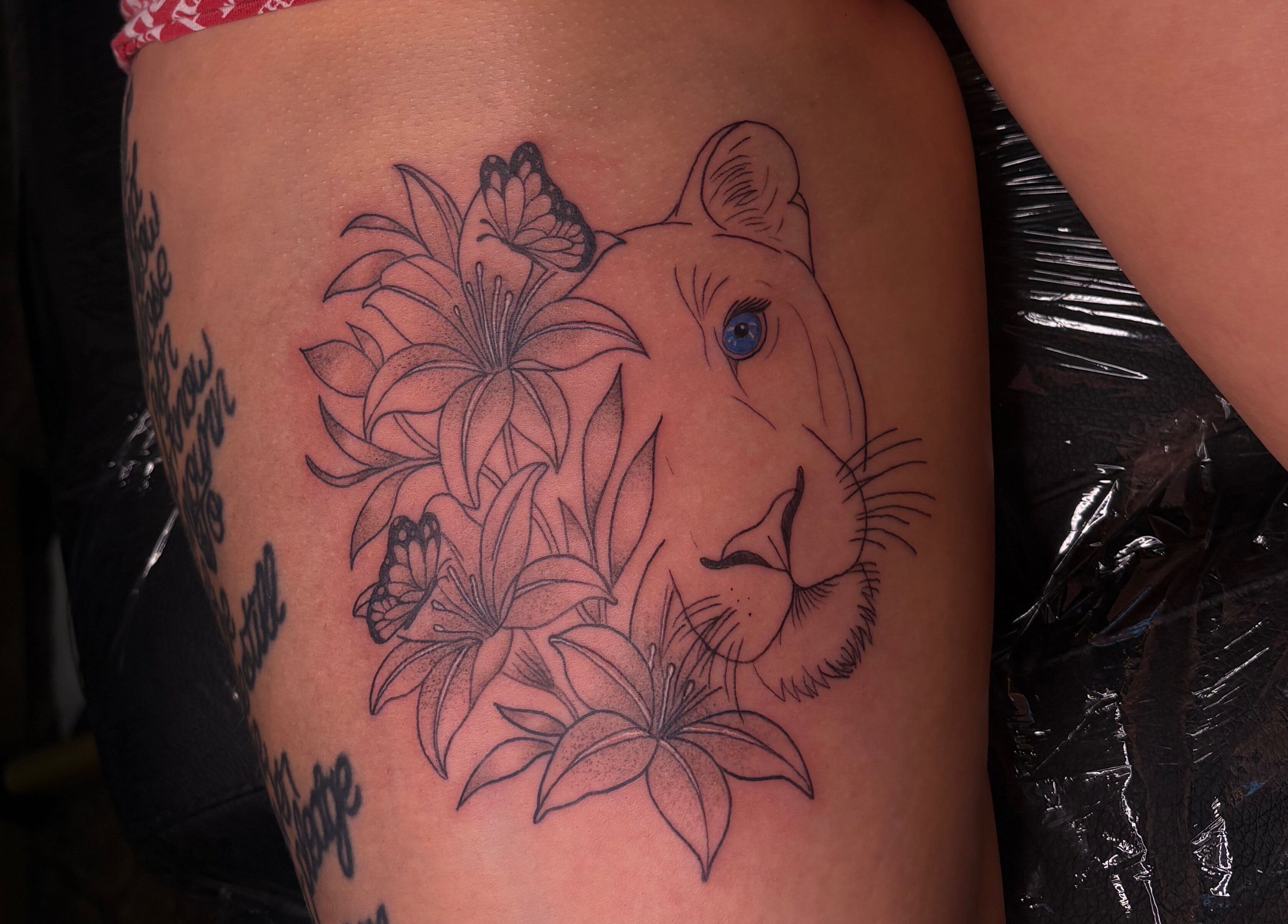 Unique lion and floral tattoo at She Studios, London, Ontario, CA, showcasing artistic body art expertise.
