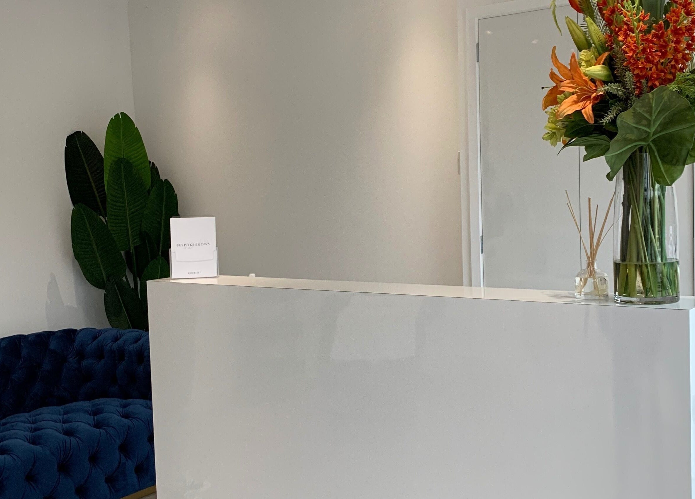 Reception area of Bespoke Brows & Aesthetics in Shirley, England, GB featuring a modern desk and vibrant flowers.