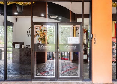 Entrance of Hair in Motion of New York - MetroWest in Orlando, Florida, US with glass doors and vibrant decor.