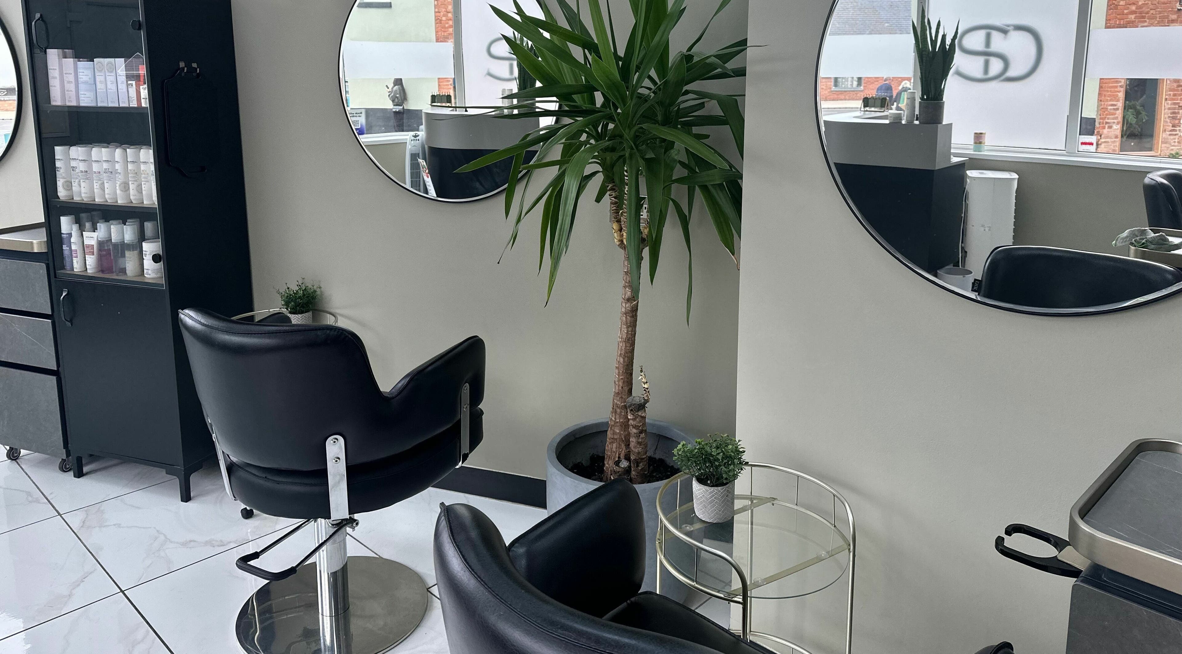 Sophisticated styling area at Shear Desire, Shepshed, England, GB featuring modern chairs and large mirrors.