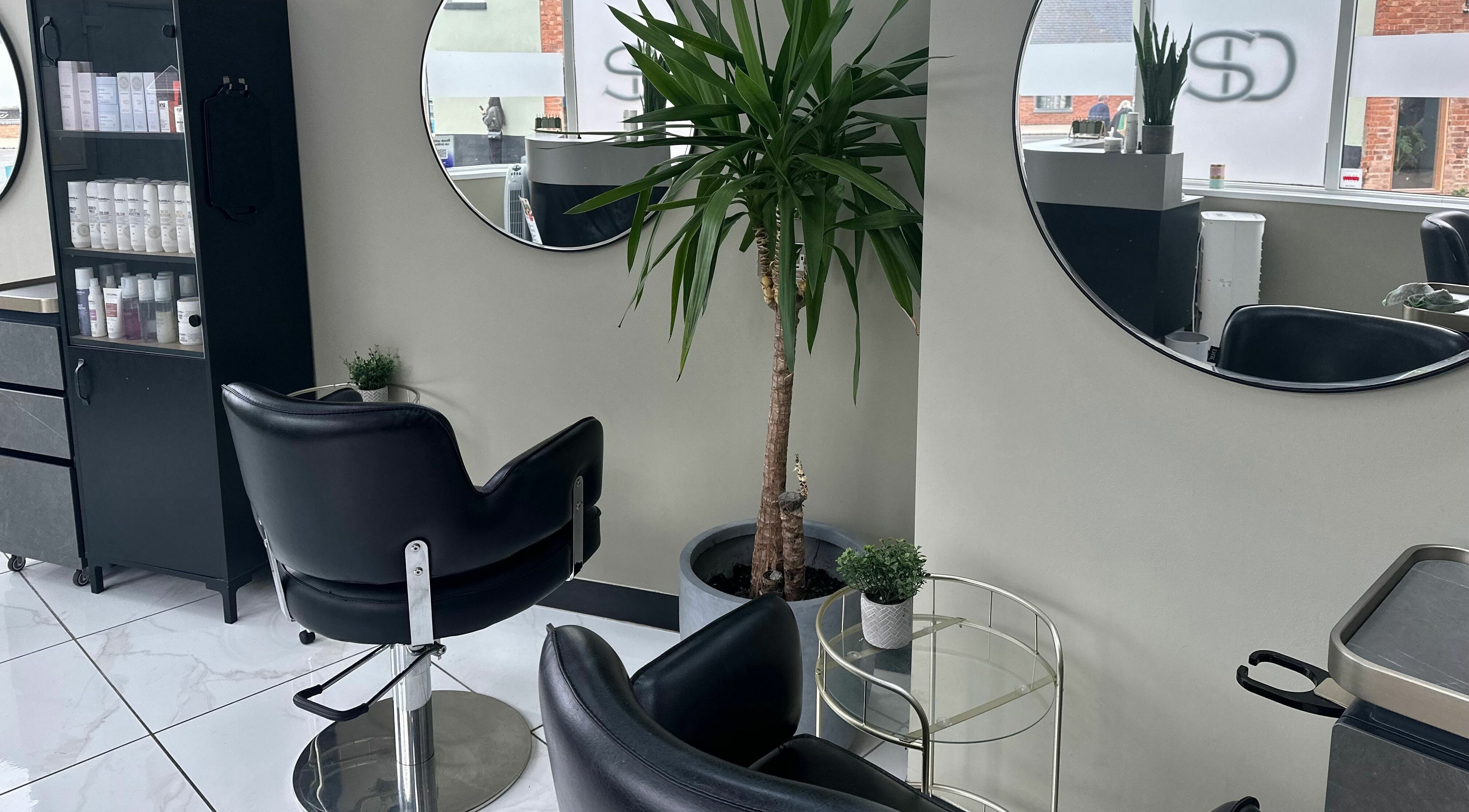 Sophisticated styling area at Shear Desire, Shepshed, England, GB featuring modern chairs and large mirrors.