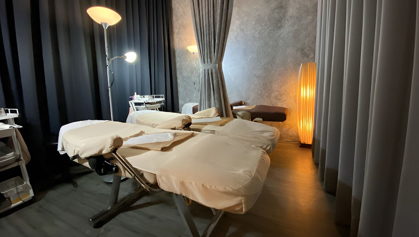 Massage room at Puttharaksa Aesthetic in Bangkok, TH with cozy lighting and soft massage tables.