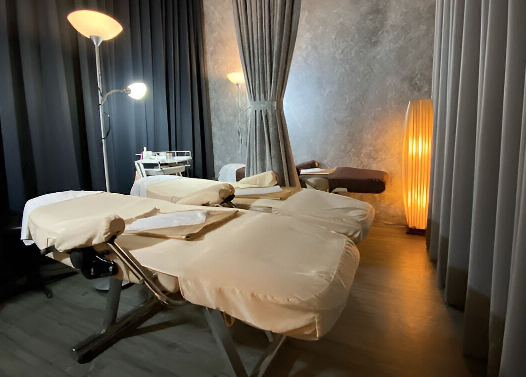 Massage room at Puttharaksa Aesthetic in Bangkok, TH with cozy lighting and soft massage tables.
