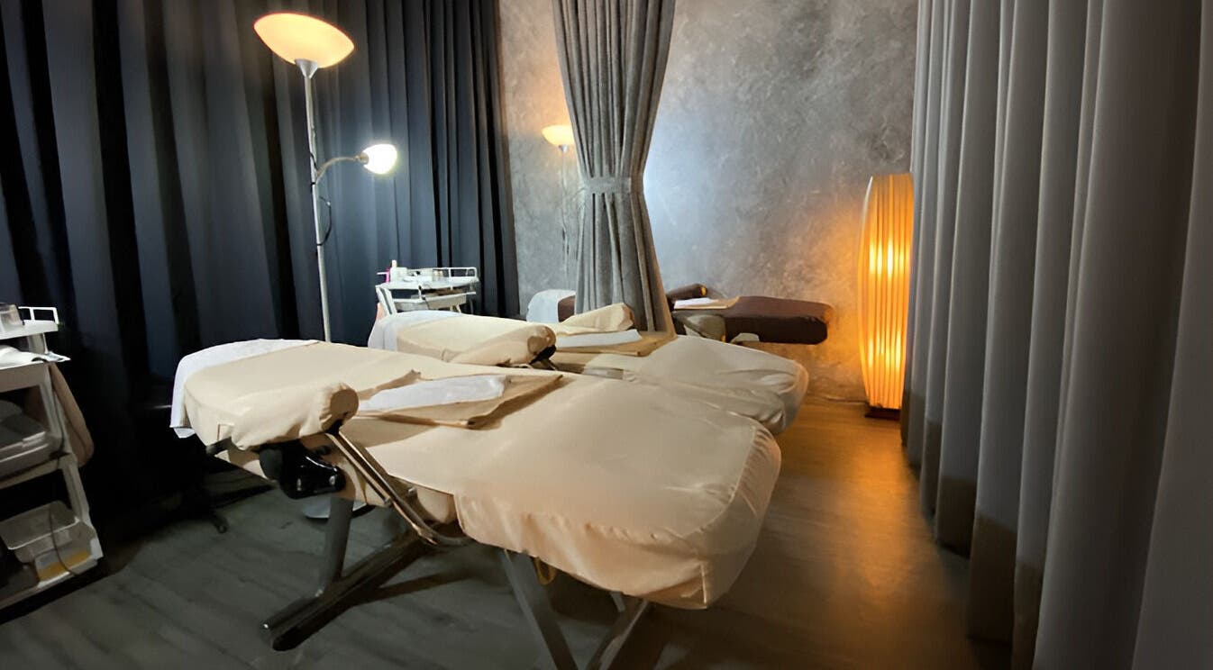 Massage room at Puttharaksa Aesthetic in Bangkok, TH with cozy lighting and soft massage tables.