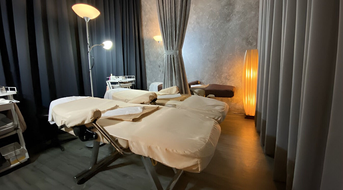 Massage room at Puttharaksa Aesthetic in Bangkok, TH with cozy lighting and soft massage tables.