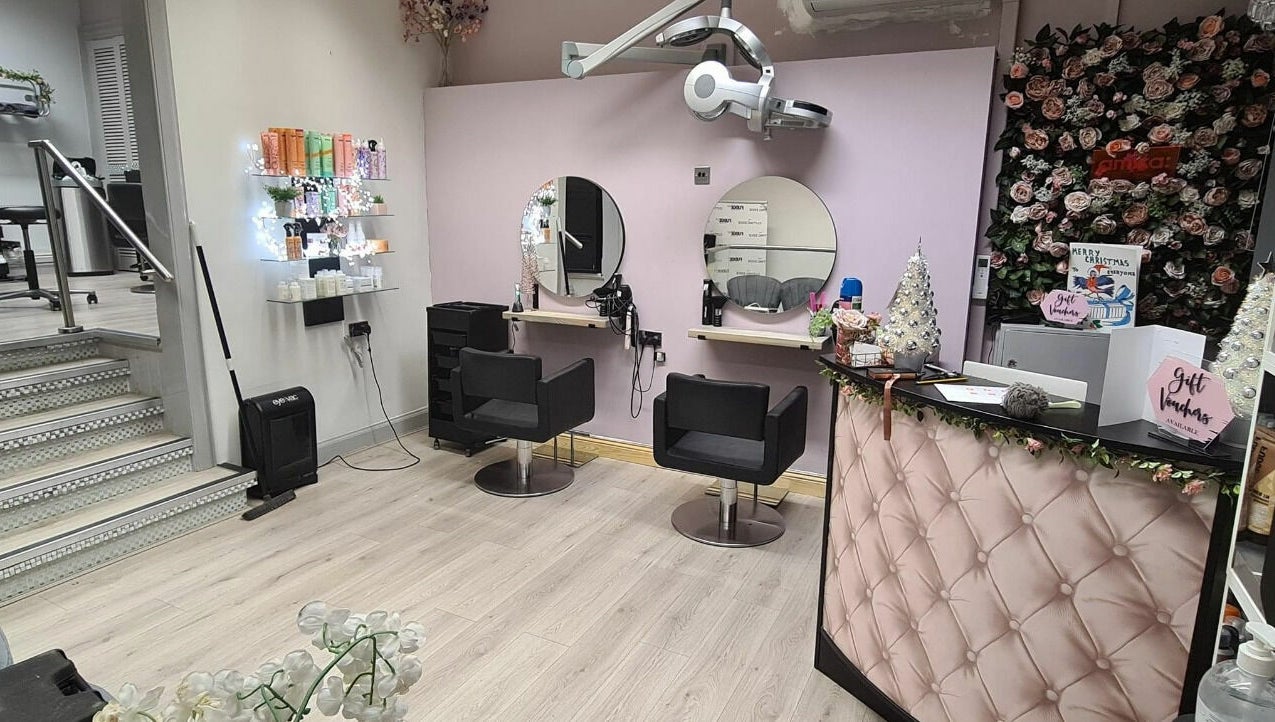 Elegant salon setup at The Cutting Edge, Dumfries, Scotland, GB. Features stylish chairs and a floral decor backdrop.