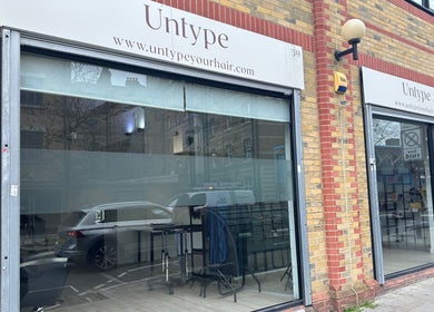 Storefront of Zateesha Barbour, London, England, GB, featuring a modern glass facade with urban brickwork.