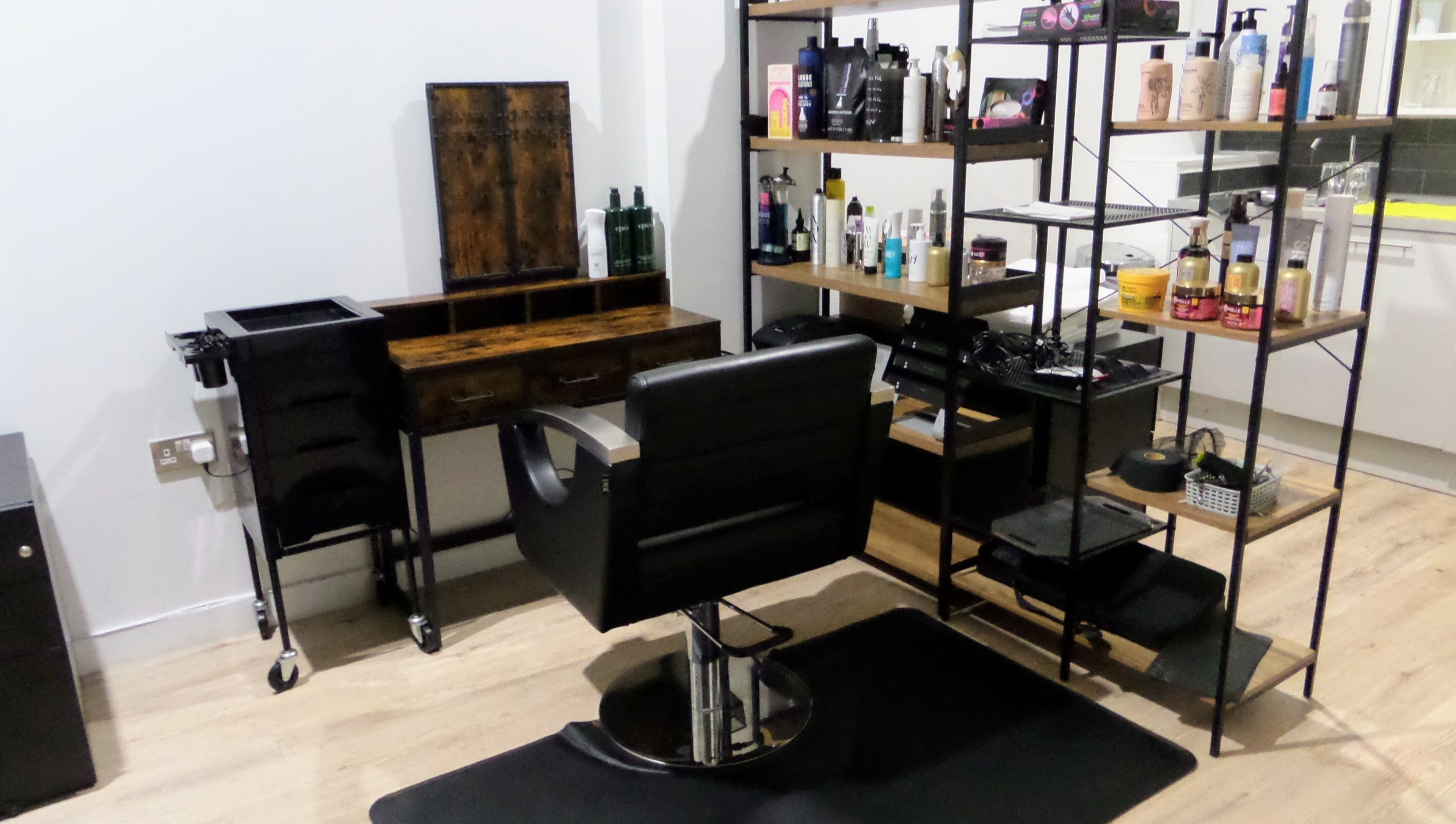 Elegant hair styling station at Zateesha Barbour, London, England, GB, featuring sleek chair and product shelves.